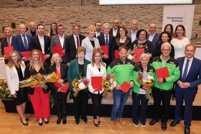 Gruppenfoto von Personen, die mit Urkunden und Blumen ausgezeichnet wurden.