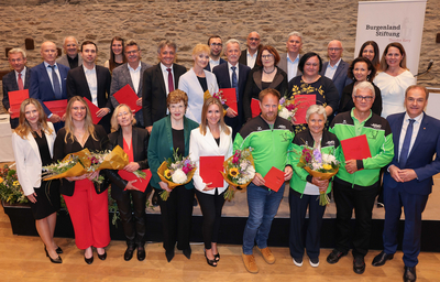 Gruppenfoto von Personen, die mit Urkunden und Blumen ausgezeichnet wurden.