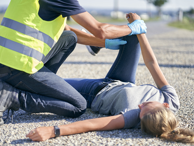 Ein Rettungssanitäter hilft einer verletzten Person auf dem Boden.