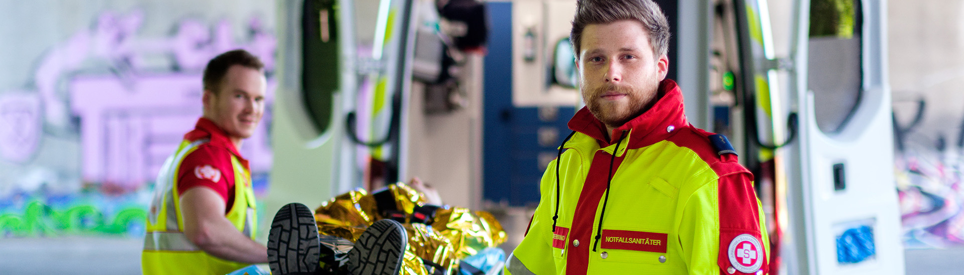 Rettungssanitäter mit Verletztem auf Trage vor Rettungsauto