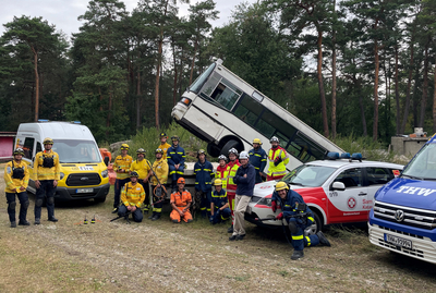 Rettungskräfte stehen vor einem umgestürzten Bus und Einsatzfahrzeugen.