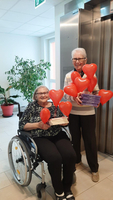 Zwei Frauen halten herzförmige Ballons und Bücher in einem hellen Raum.