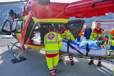 Rettungskräfte transportieren eine Trage in einen Rettungshubschrauber.