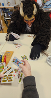 Person in einem Tierkostüm spielt Karten mit einer weiteren Person am Tisch.