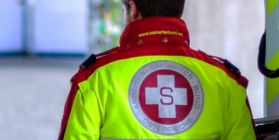 Ein Sanitäter in rot-gelber Uniform mit dem Logo des Samariterbundes.