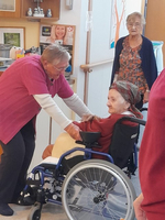 Pflegekraft unterstützt älteren Menschen im Rollstuhl in einer Einrichtung.