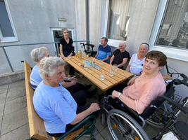 Eine Gruppe von Senioren sitzt an einem Tisch im Freien.
