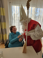 Eine ältere Frau lacht und spricht mit einem Nikolaus.