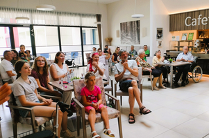 Eine Gruppe von Menschen sitzt in einem Café und applaudiert begeistert.