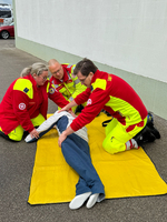 Drei Sanitäter führen eine Übung mithilfe einer Übungspuppe durch.