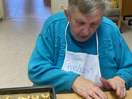 Eine ältere Frau formt Plätzchen auf einem Backblech.