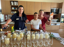 Drei Personen bereiten Drinks in einer modernen Küche vor.