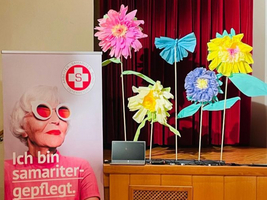 Bunte Papierblumen und ein Plakat mit dem Slogan 
