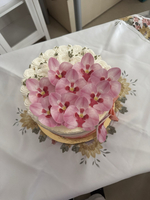 Eine Torte dekoriert mit rosa Orchideenblüten und cremefarbener Buttercreme.