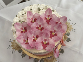 Eine Torte dekoriert mit rosa Orchideenblüten und cremefarbener Buttercreme.