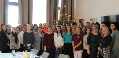Gruppenfoto von Mitarbeitern vor einem geschmückten Weihnachtsbaum.