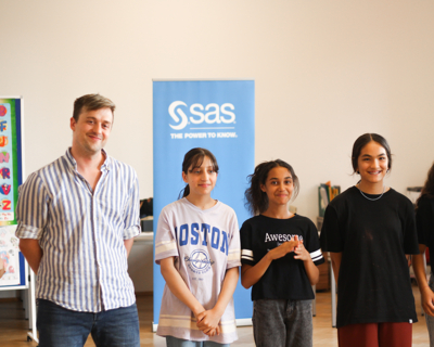 Drei Kinder und ein Erwachsener stehen in einem Raum vor einem SAS Roll-up, LernLEO, Event, Tanzworkshop