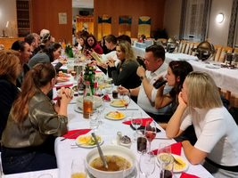 Eine Gruppe von Menschen sitzt an einem langen Tisch bei einem gemeinsamen Essen.