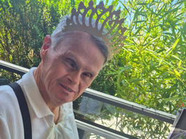 Mann mit Krone genießt ein Gericht und Salat im Freien.