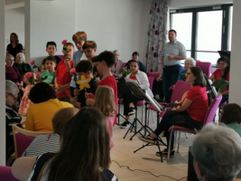 Kinder führen eine Aufführung für Senioren in einem Gemeinschaftsraum auf.