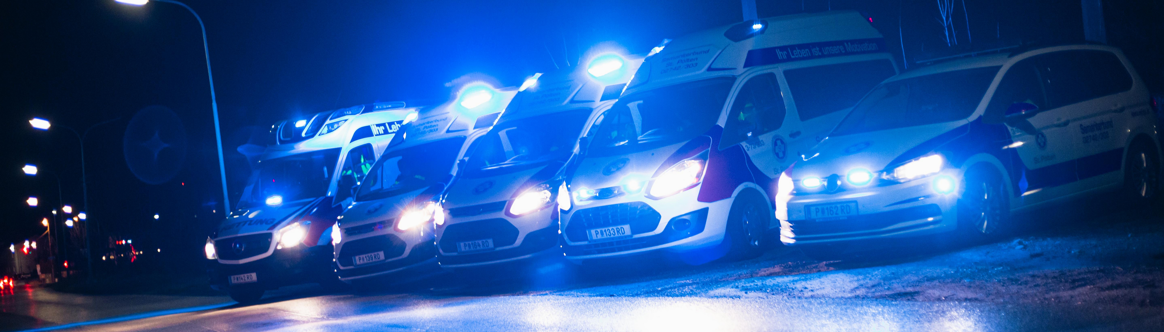 Blaulichtfahrzeuge auf einer Straße, nachts beleuchtet.