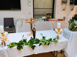 Ein Tisch mit religiösen Symbolen, Kerzen, Blumen und Dekorationen.