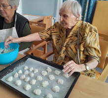 Zwei ältere Damen bereiten gemeinsam Kokosmakronen in einer Einrichtung vor.