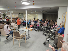 Eine Gruppe älterer Menschen sitzt und schaut einer Unterhaltung zu.