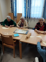 Ältere Frauen backen gemeinsam und formen Teig an einem Tisch.