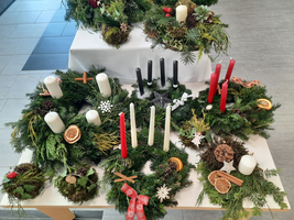 Zahlreiche dekorierte Adventskränze mit Kerzen und festlichem Schmuck.