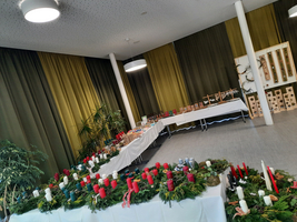 Eine festliche Dekoration mit Kerzen und grünen Kränzen in einem Raum.