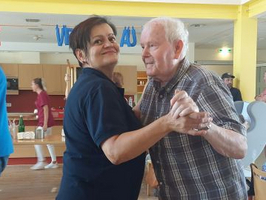 Ein Mann und eine Frau tanzen gemeinsam glücklich in einem hellen Raum.