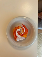 Bunte, faltige Papierrose auf einem weißen Teller.