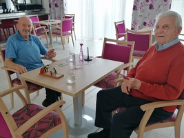 Zwei ältere Männer sitzen am Tisch und spielen Karten.