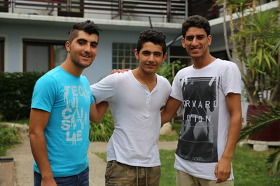 3 junge Flüchtlinge vor dem Flüchtlingshaus
