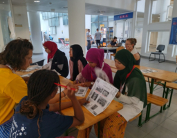 eine Gruppe von Kindern sitzt gemeinsam am Tisch, arbeiten an Aufgabe