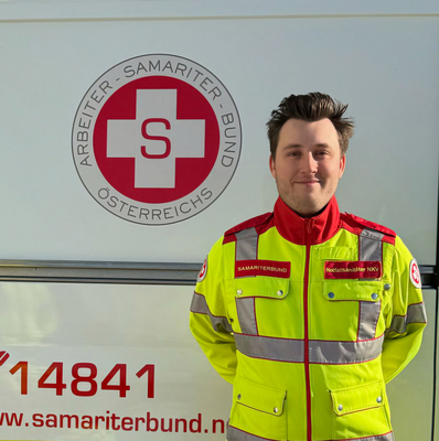 Ein Sanitäter in Uniform steht vor einem Rettungsauto des Samariterbundes.