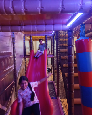 Aufnahme von zwei LernLEO-Kindern in einem Indoor-Spielraum, Innenbereich, auf Rutsche