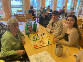Drei Personen spielen ein Brettspiel in einer freundlichen Umgebung.