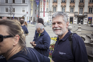 Gruppe von Menschen in blauen T-Shirts, einer lächelt freundlich in die Kamera.