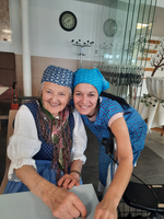 Eine ältere Frau und eine jüngere Frau lächeln zusammen am Tisch.