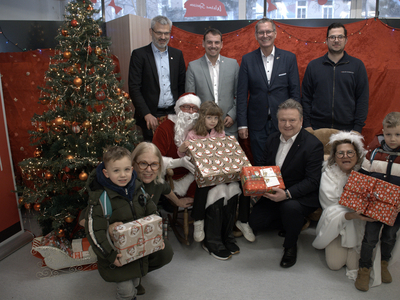 Elf Personen mit Christbaum und Weihnachtsgeschenken im Sozialmarkt des Samariterbundes Wien