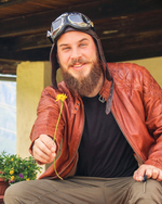 Mann in Lederjacke bietet eine Blume lächelnd an.