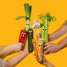 Vier Hände halten je ein Stück Gemüse mit aufgeklebten Augen