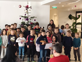 Eine Gruppe von Kindern singt vor einem Weihnachtsbaum.