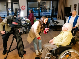 Ein Fernsehteam interviewt einen Rollstuhlfahrer in einem Seniorenheim.