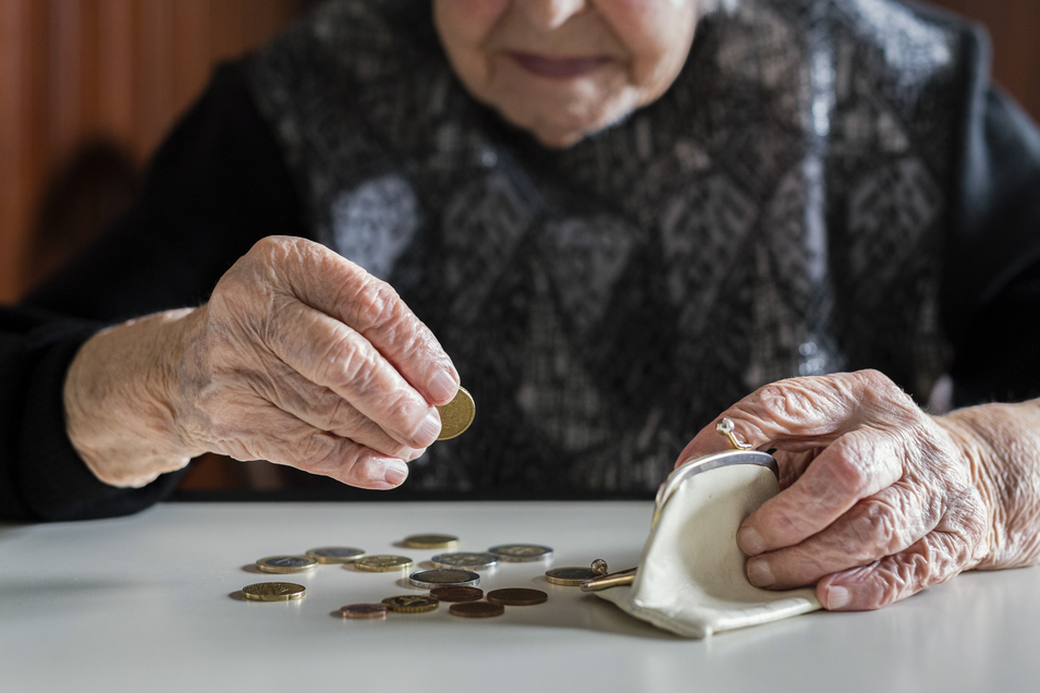 Ältere Frau zählt Münzen auf Küchentisch