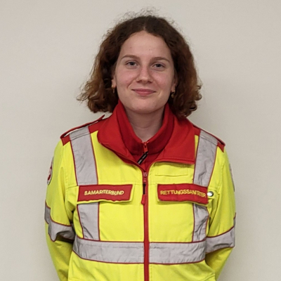 Junge Frau in Rettungsdienstuniform lächelt freundlich in die Kamera.