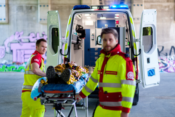 Zwei Samariterbund-Sanitäter mit Patienten auf der Krankentrage vor einem Rettungswagen