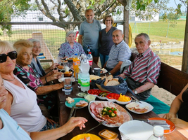 Eine Gruppe von Menschen genießt ein gemeinsames Essen im Freien.